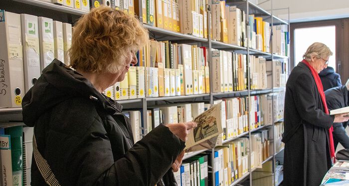 Dame leser innhold i arkivet. Hyller med dokumenter