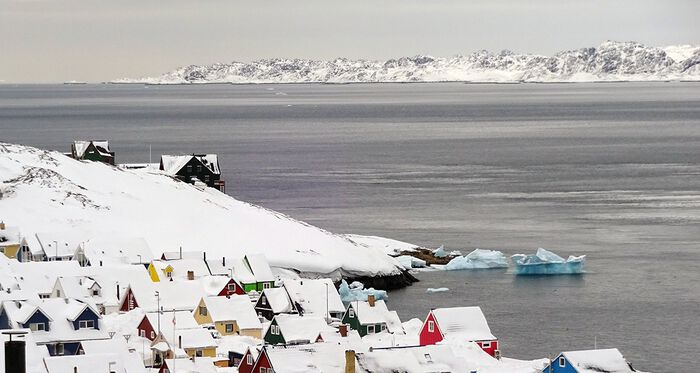 Foto av snødekkede hus ved kysten. Snø, fjell, hav. 